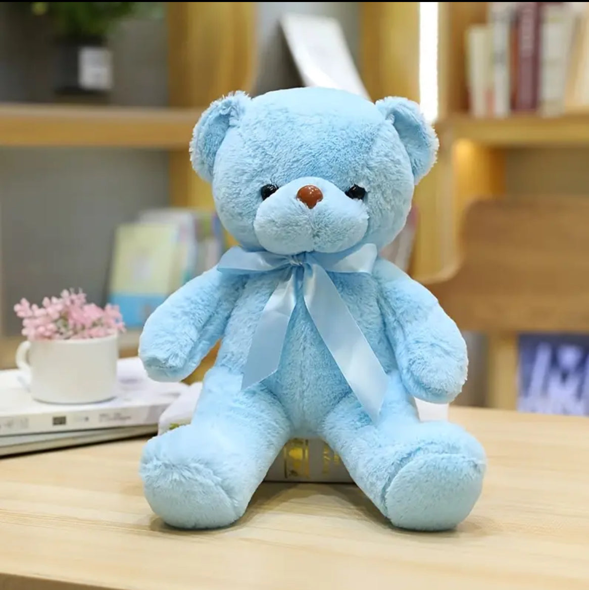 A blue-coloured teddy bear with a satin ribbon bow around its neck.