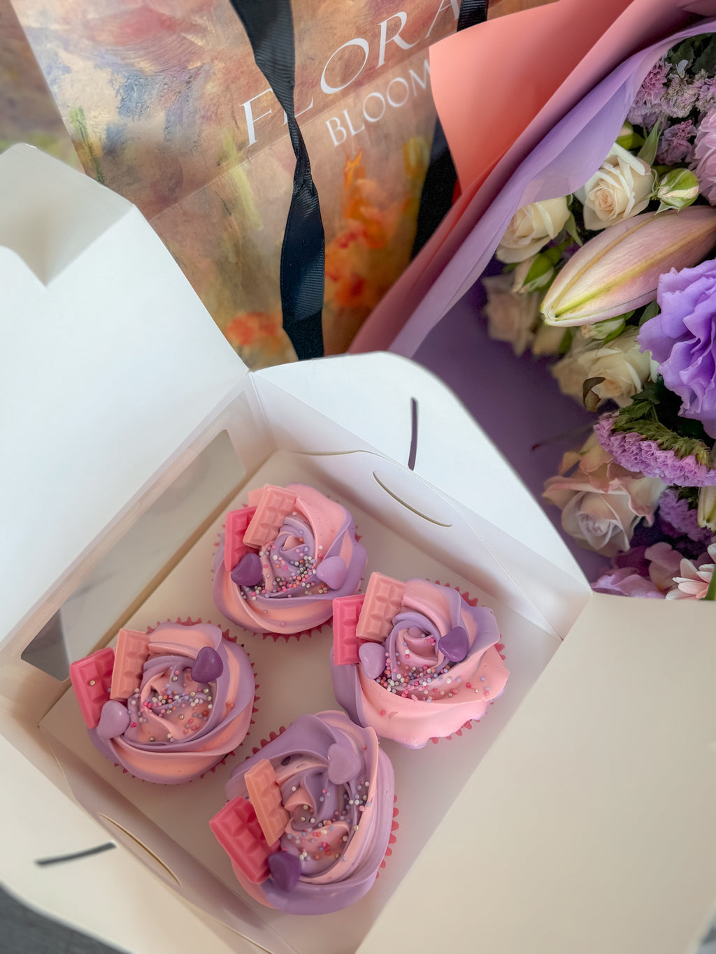 Decorative cupcakes in a box with flowers in the background
