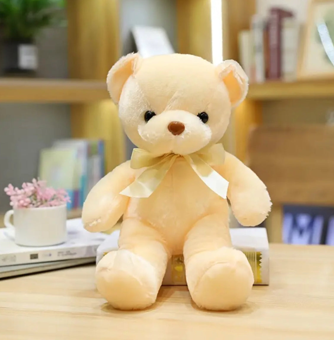 A cream-coloured teddy bear with a satin ribbon bow around its neck.
