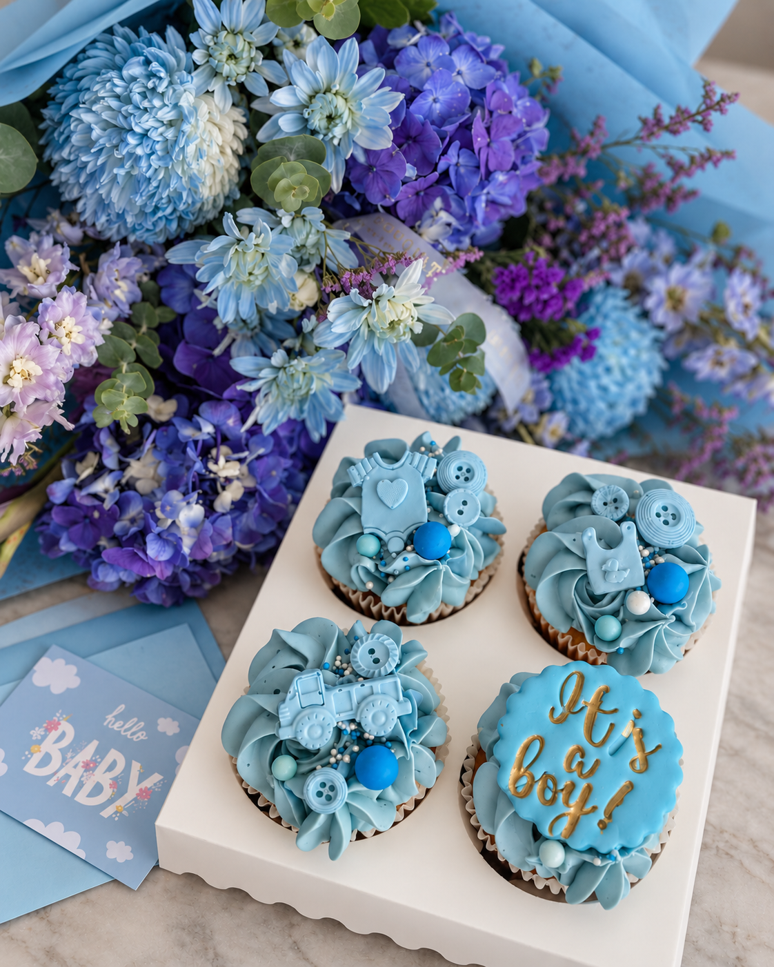 Close-up of four blue baby-themed cupcakes with flowers