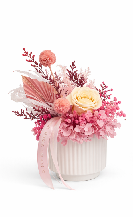 A small floral arrangements with pink and white flowers in white ceramic vase